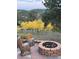 Charming backyard with a stone fire pit and log furniture surrounded by aspen trees at 351 N Saddle Dr, Idaho Springs, CO 80452