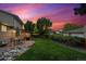 The backyard offers a patio, an expansive lawn, mature trees, lush foliage and a stone border at 13266 Canopus Dr, Lone Tree, CO 80124