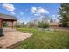 A spacious backyard with a stone patio, raised garden beds, and lush green lawn at 5481 E Tennessee Ave, Denver, CO 80246