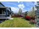 Well-maintained backyard with lush green grass, colorful flowering trees, and a wood fence at 10733 Salida St, Commerce City, CO 80022