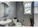 Half bathroom with gray walls, round mirror, and pedestal sink at 10733 Salida St, Commerce City, CO 80022