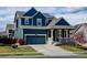 Charming blue two-story home featuring a covered front porch, blue garage door, and a well-manicured lawn at 10733 Salida St, Commerce City, CO 80022
