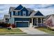 Charming blue two-story home featuring a covered front porch, blue garage door, and a well-manicured lawn at 10733 Salida St, Commerce City, CO 80022
