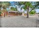 Cozy brick home showcasing a meticulously graveled front yard, mature trees and side driveway at 61 S 17Th Avdr, Brighton, CO 80601