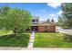 Inviting two-story brick home featuring a well-manicured lawn, mature shade tree, and welcoming front porch at 6918 E Long Ave, Centennial, CO 80112