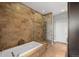 Large bathroom showcasing a soaking tub, glass-enclosed shower, and travertine tile walls at 7600 Landmark Way # 1215, Greenwood Village, CO 80111