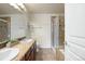 Well-lit bathroom with a dual sink vanity, tile flooring, and a glass-enclosed shower and tub at 7662 Bristolwood Dr, Castle Pines, CO 80108