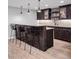 Finished basement wet bar with wood floors, dark cabinets, pendant lights, and seating for three at 445 Brendon Ct, Castle Pines, CO 80108