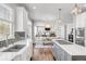 Open-concept kitchen with an island, white cabinets, stainless steel appliances, and a view of the dining and living areas at 445 Brendon Ct, Castle Pines, CO 80108