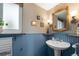 Charming bathroom featuring blue beadboard, pedestal sink, and wood-framed mirror at 537 S Grape St, Denver, CO 80246