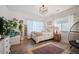 Bright bedroom featuring neutral tones, a large window, decorative light fixture, and hardwood floors at 7007 S Garrison St, Littleton, CO 80128