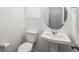 Bathroom features a pedestal sink, round mirror, and white walls at 3365 N Coolidge Way, Aurora, CO 80019