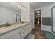 Well-lit bathroom featuring double sinks, granite countertops, and a tiled floor with an adjacent walk-in closet at 42855 Hawktree Cir, Elizabeth, CO 80107