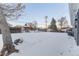 Large, snow-covered backyard with fencing and mature trees at 121 Joan Dr, Denver, CO 80221