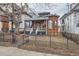 Charming brick home featuring a welcoming front porch and a classic black wrought iron fence at 1229 Josephine St, Denver, CO 80206
