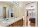 Bright bathroom featuring double vanity with a large mirror and a view into the primary bedroom at 10726 Amesbury Way, Highlands Ranch, CO 80126