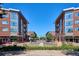 Lush street view of modern brick apartments with a variety of restaurants and shops on the ground level at 2835 N Monaco Pkwy, Denver, CO 80207