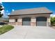 Spacious two-car garage with stone accents and an adjacent greenhouse on a sunny day at 2916 Hiwall Ct, Castle Rock, CO 80109
