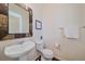 Powder room featuring a decorative framed mirror, pedestal sink, and a neutral color palette at 2936 Iola St, Denver, CO 80238