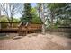Multi-level wood deck with natural landscaping featuring red gravel and mature trees in the backyard at 6274 S Iola Ct, Englewood, CO 80111