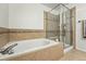 Bathroom features tub, glass enclosed shower and decorative tile work at 5574 W 72Nd Dr, Arvada, CO 80003