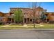 A row of townhouses with wood and stone exteriors, featuring individual covered entrances and landscaping at 5574 W 72Nd Dr, Arvada, CO 80003
