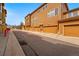 Multi-story townhome featuring attached garages, wood siding, and a paved driveway under a blue sky at 5574 W 72Nd Dr, Arvada, CO 80003