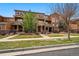 Three-story townhouses with stone accents and wooden balconies surrounded by greenery and lawn at 5574 W 72Nd Dr, Arvada, CO 80003