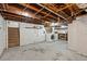 Unfinished basement with painted brick walls, exposed wood ceiling, laundry, and storage space at 1031 S Pennsylvania St, Denver, CO 80209