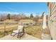 A patio chair sits on a concrete slab in the backyard with a white fence and green space at 14944 E Archer Cir, Aurora, CO 80012