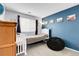 Carpeted bedroom features a blue accent wall, a daybed, a crib, and a black beanbag chair at 14944 E Archer Cir, Aurora, CO 80012