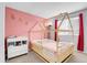 Cute bedroom featuring a pink accent wall, house-style bed, and adjacent changing table at 14944 E Archer Cir, Aurora, CO 80012