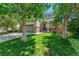 Inviting home with lush green lawn, mature trees, and a brick-accented facade and front-facing two car garage at 14944 E Archer Cir, Aurora, CO 80012