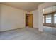 Bedroom featuring neutral carpet, a large window with blinds, and a doorway leading to an adjacent room at 9784 W Euclid Dr, Littleton, CO 80123