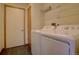 Bright laundry room with white washer and dryer and overhead shelving at 9784 W Euclid Dr, Littleton, CO 80123