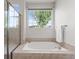 Bright bathroom featuring a bathtub, tiled surround, shower and large window at 9162 W Unser Ave, Littleton, CO 80128