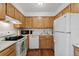 Functional kitchen featuring white appliances, wooden cabinets, and ample counter space at 11905 E Harvard Ave # 208, Aurora, CO 80014