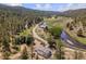 Aerial view of a home by a river, amidst lush trees, green fields and a winding road at 2230 S Platte River Rd, Sedalia, CO 80135