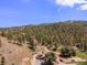 Aerial shot of a charming house nestled in a forest with views of rolling hills and mountains at 2230 S Platte River Rd, Sedalia, CO 80135