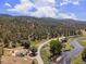 Aerial shot showcasing a riverfront property with winding road, set against a lush forest backdrop at 2230 S Platte River Rd, Sedalia, CO 80135