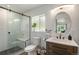 Bright bathroom featuring a glass shower, tiled walls, floating vanity, and round mirror at 2230 S Platte River Rd, Sedalia, CO 80135