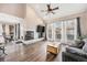 Bright living room with a cozy fireplace, and floor-to-ceiling windows dressed with elegant curtains at 13421 Humboldt Way, Thornton, CO 80241