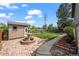 A well-maintained backyard with a water fountain, a shed, green grass, and a stone sidewalk at 5338 Granby St, Denver, CO 80239