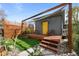 Backyard building with a deck and a bright yellow door surrounded by a wooden trellis at 3368 S Corona St, Englewood, CO 80113