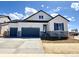 Charming two-story home with a three car garage, stone accents, and black trim against white siding at 25204 E Warren Pl, Aurora, CO 80018