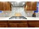 Close up of a kitchen featuring a stainless steel gas range with stainless vent hood and mosaic backsplash at 2775 Morningbird Ln, Castle Rock, CO 80109