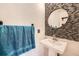 Stylish powder room featuring a sleek pedestal sink, decorative tile accent wall, and round mirror at 5163 Apache Creek Rd, Castle Rock, CO 80109
