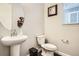 Charming half bathroom with pedestal sink, round mirror, and dark wood flooring at 1403 Hart Ln, Elizabeth, CO 80107