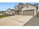 Long, wide driveway leading up to a three-car garage of a home with a charming front porch and stone accents at 1403 Hart Ln, Elizabeth, CO 80107