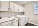 Bright laundry room features white cabinets, sink, modern washer and dryer set at 1403 Hart Ln, Elizabeth, CO 80107
